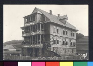 b&w photo of a wooden three-story home with girls lining the balcony