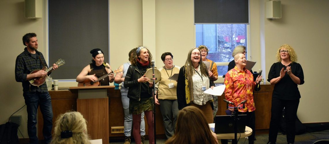 Front Left to Right: Basya Schechter, Naomi Seidman, M Miller and Pearl Gluck. Back row Kol Isha choir with participant Dainy Berstein directly between Basya Schechter and Naomi Seidman